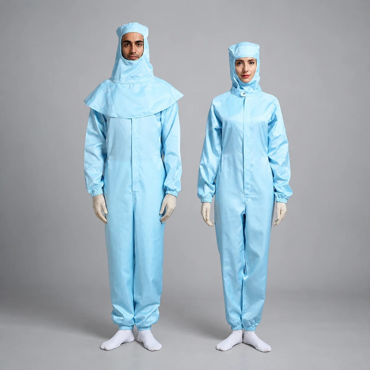 Two operators wearing light-blue cleanroom coveralls with different hood configurations